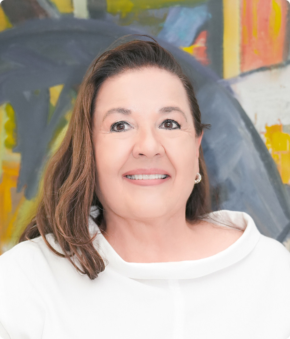 Smiling woman with brown hair in a white blouse, posed in front of a colorful mural background.